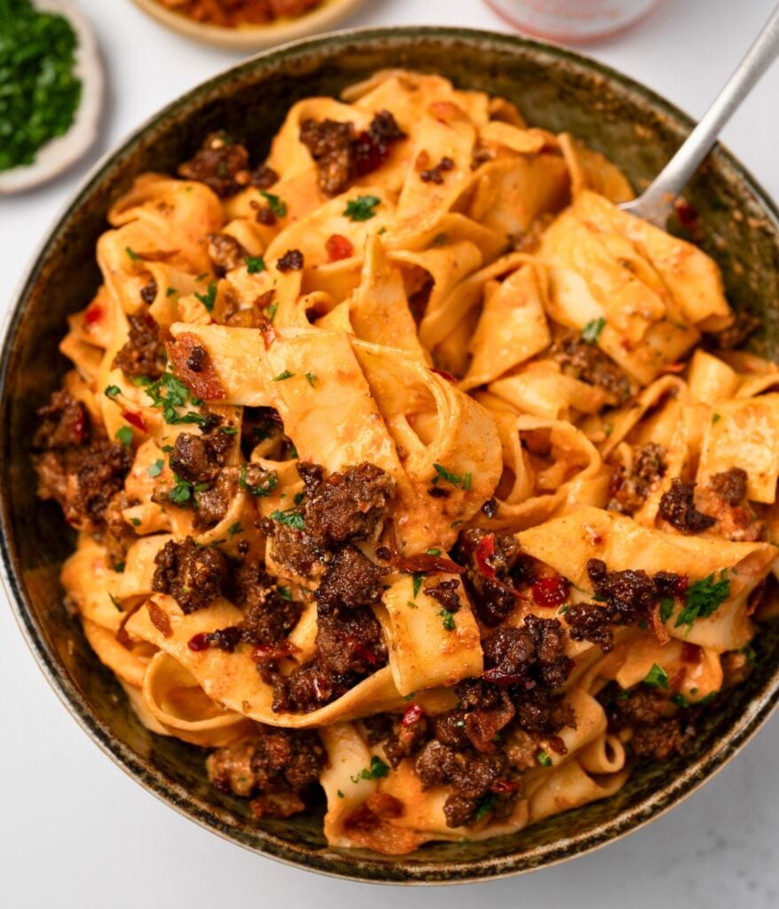 a bowl of red pepper cottage cheese pasta with a fork in it