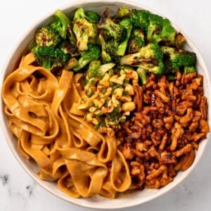 peanut butter noodles in a bowl with ground chicken, broccoli, and chopped peanut salad