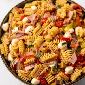 a green bowl filled with deli style high protein pasta salad