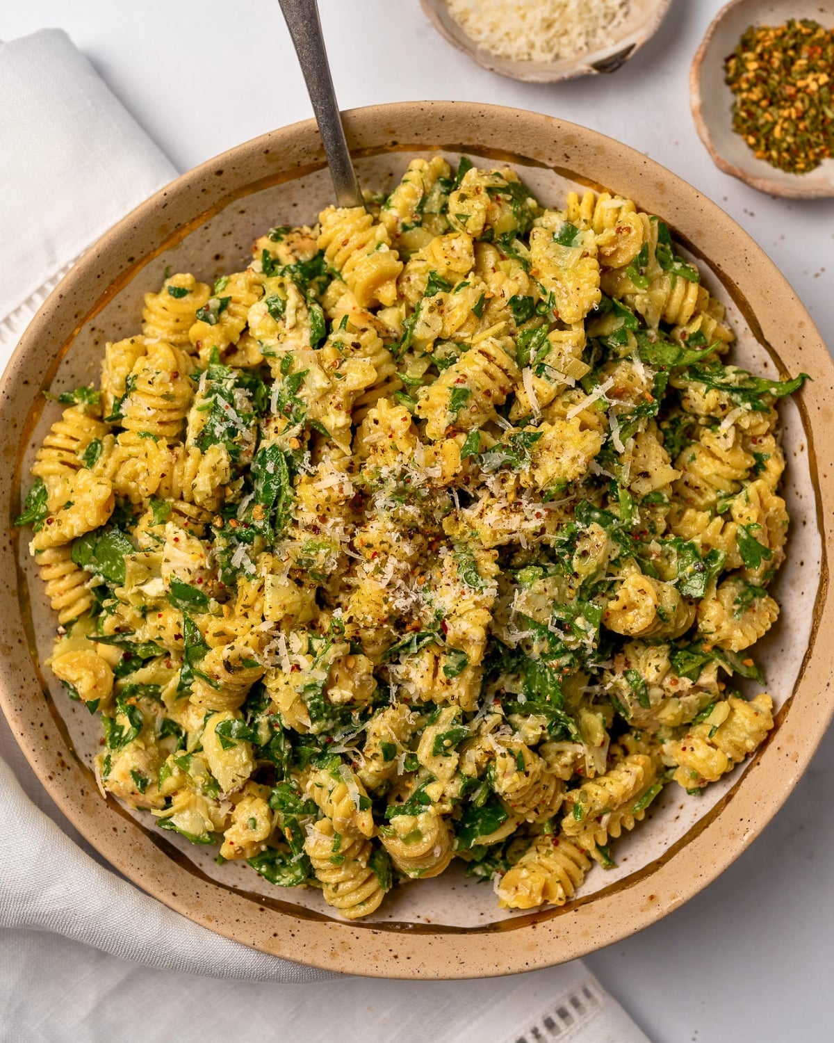 lemon parmesan chicken pasta salad in a bowl garnished with grated parmesan and black pepper