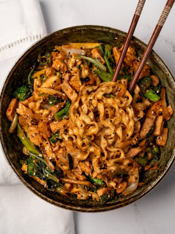 chicken stir fry noodles in a green bowl with chopsticks