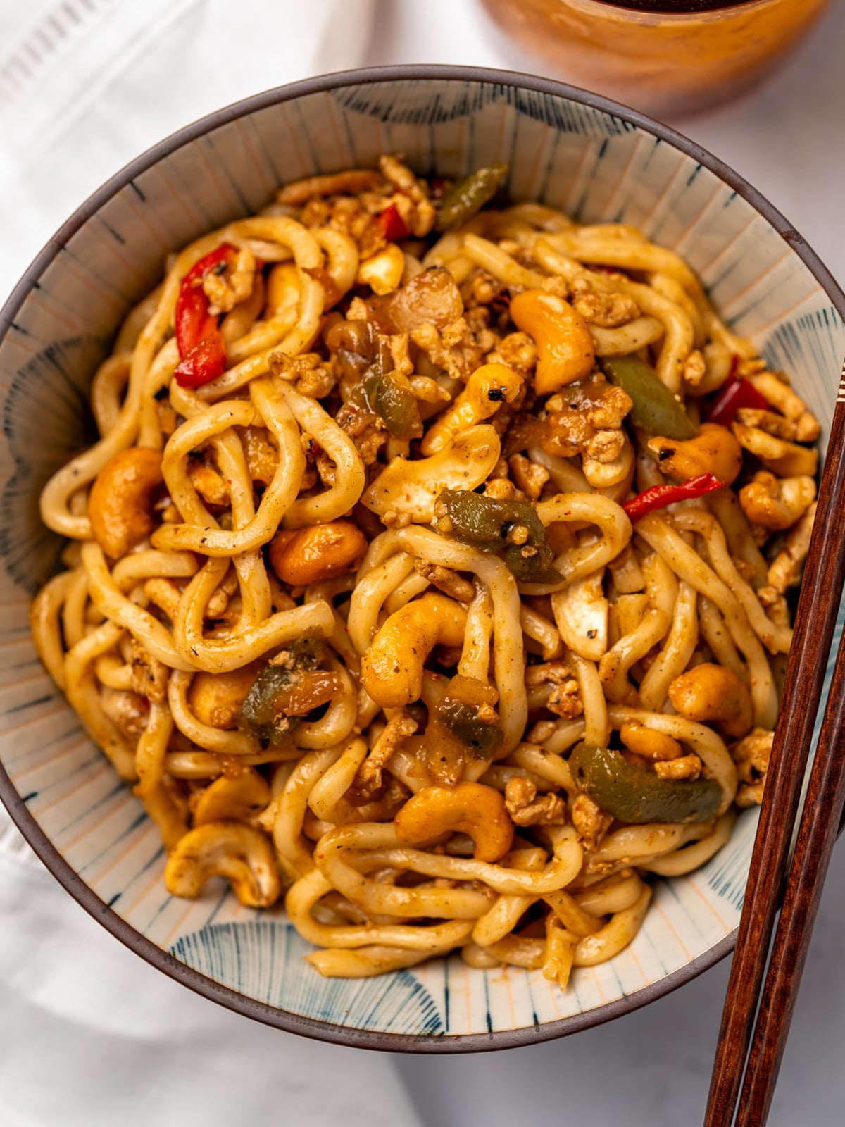 cashew chicken noodles in a bowl with chopsticks