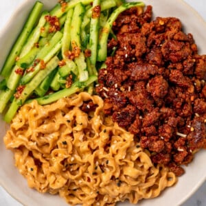 creamy sesame noodles, spicy beef, and cucumber herb salad in a bowl