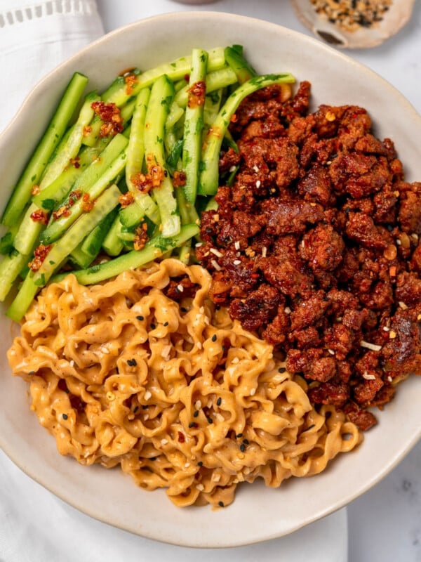creamy sesame noodles, spicy beef, and cucumber herb salad in a bowl