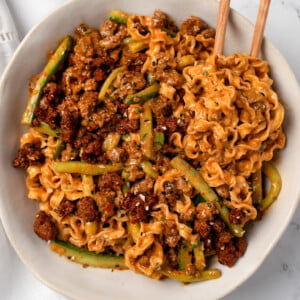 sesame noodles in a bowl mixed with spicy beef and sliced cucumbers
