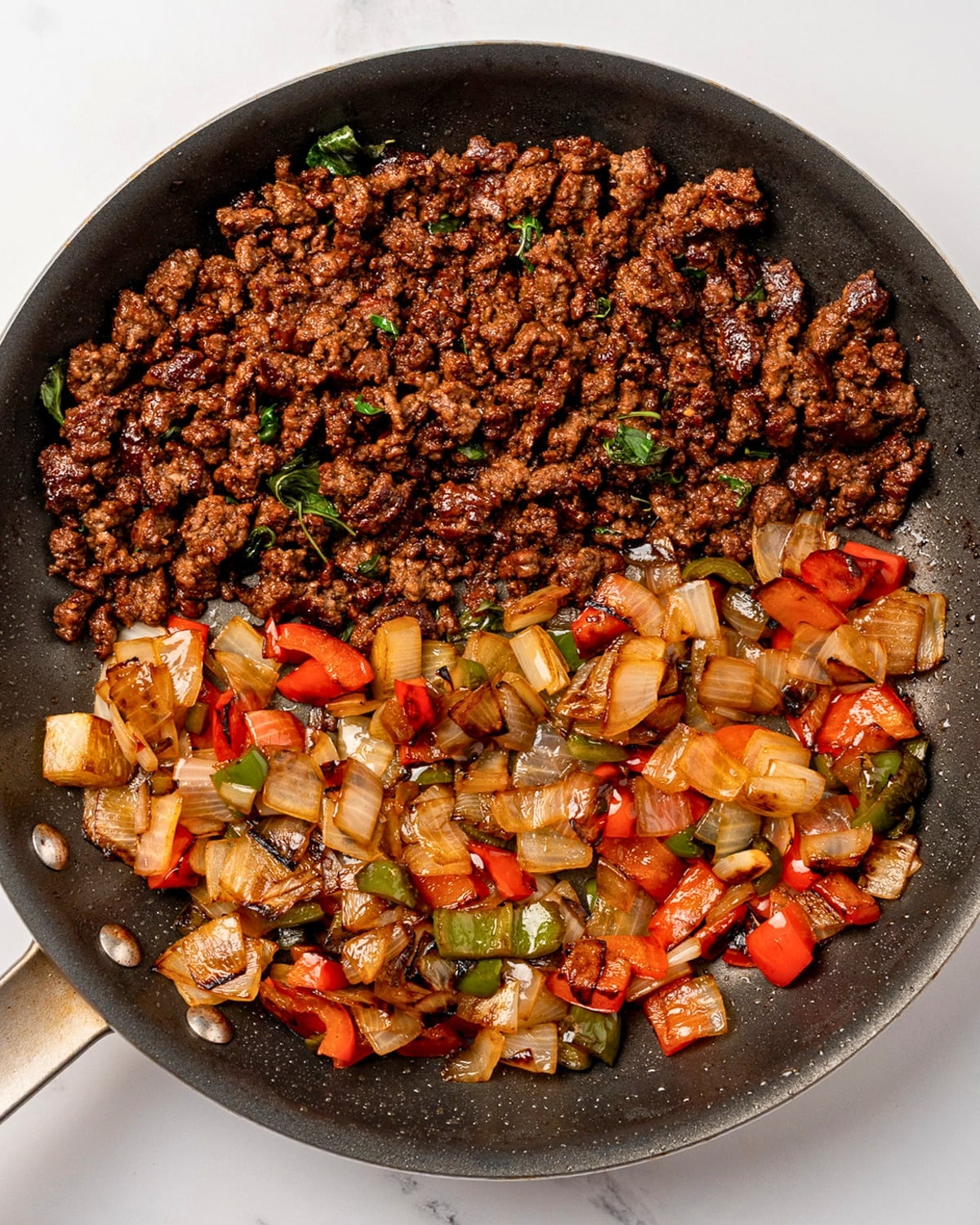Thai basil ground beef in a pan with stir fried onion and peppers