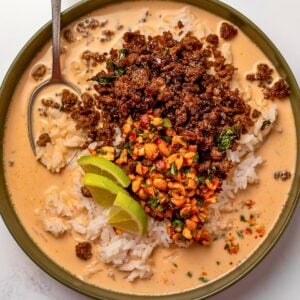 steamed rice, Thai basil ground beef, coconut peanut broth, chopped peanut garnish, and lime wedges in a green bowl