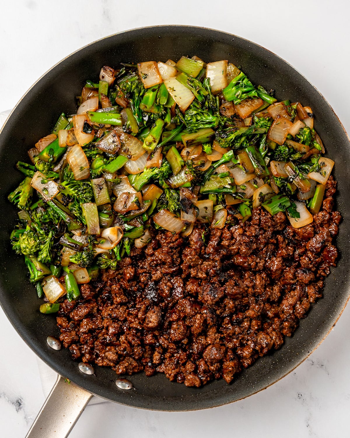 stir fried broccolini and onion with crispy hoisin ground beef in a nonstick pan