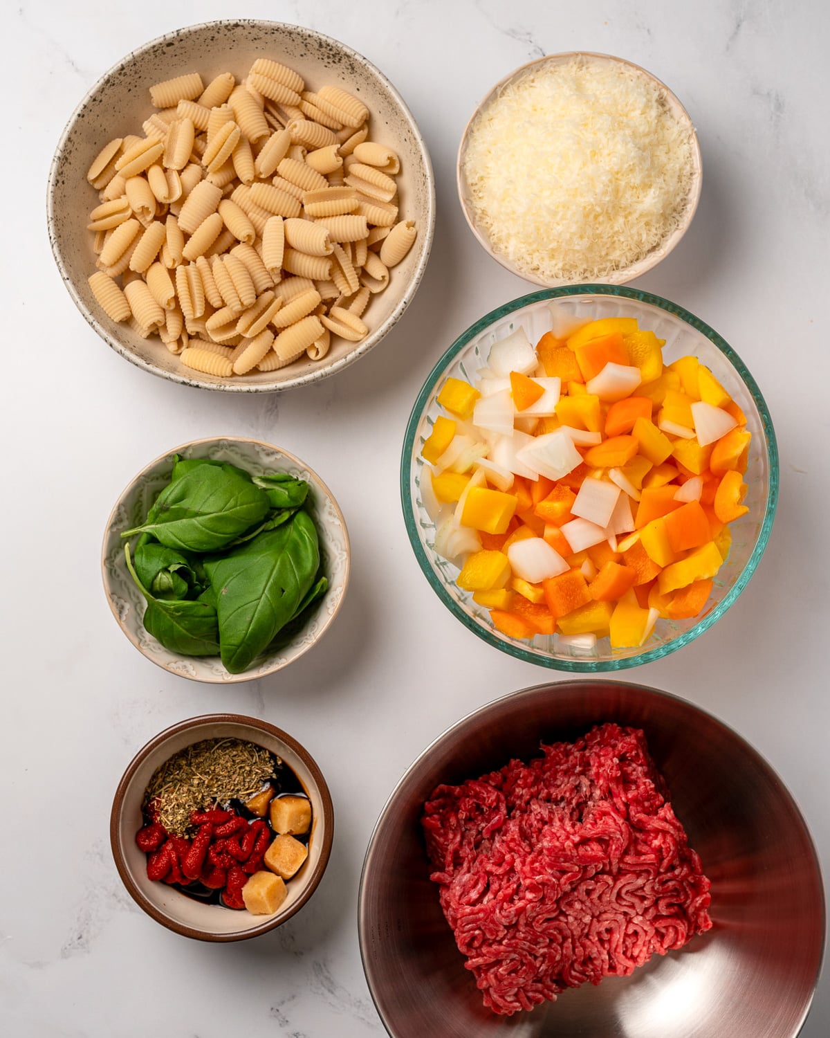 lean ground beef, diced onion and bell peppers, parmesan cheese, fresh basil, cavatelli, and a bowl of tomato paste, balsamic vinegar, garlic, and Italian seasoning