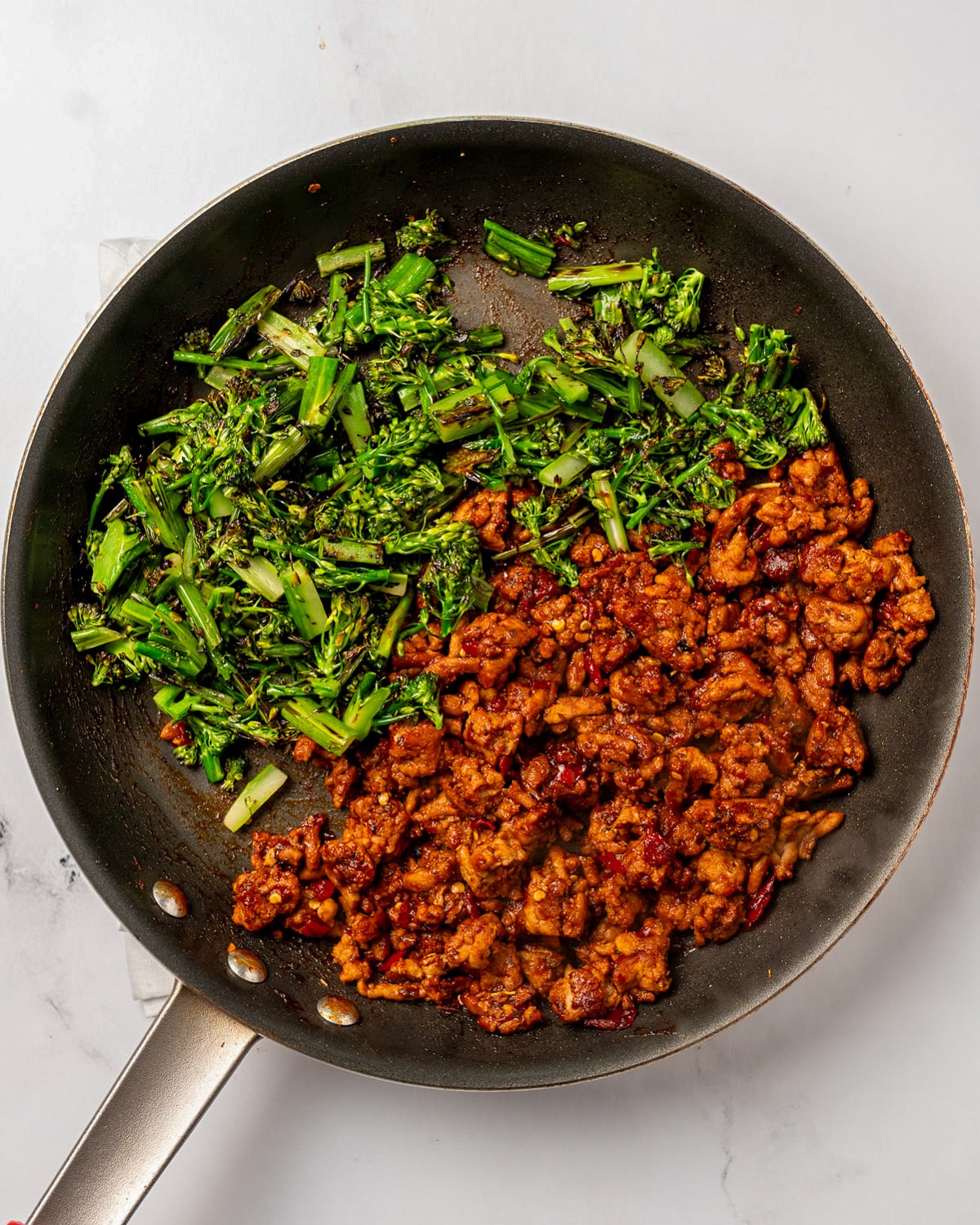 Calabrian chili ground chicken in a pan with roasted broccolini 