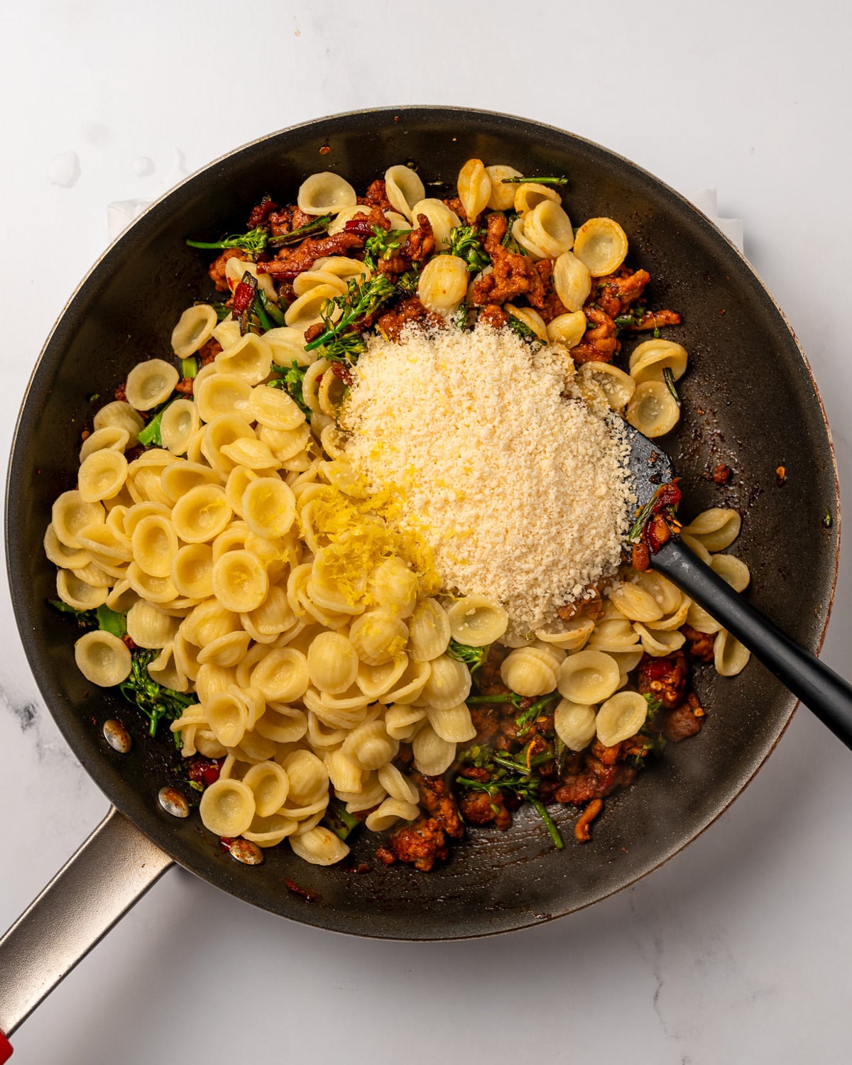 cooked pasta, grated parmesan, and lemon zest in a pan with Calabrian chicken and broccolini