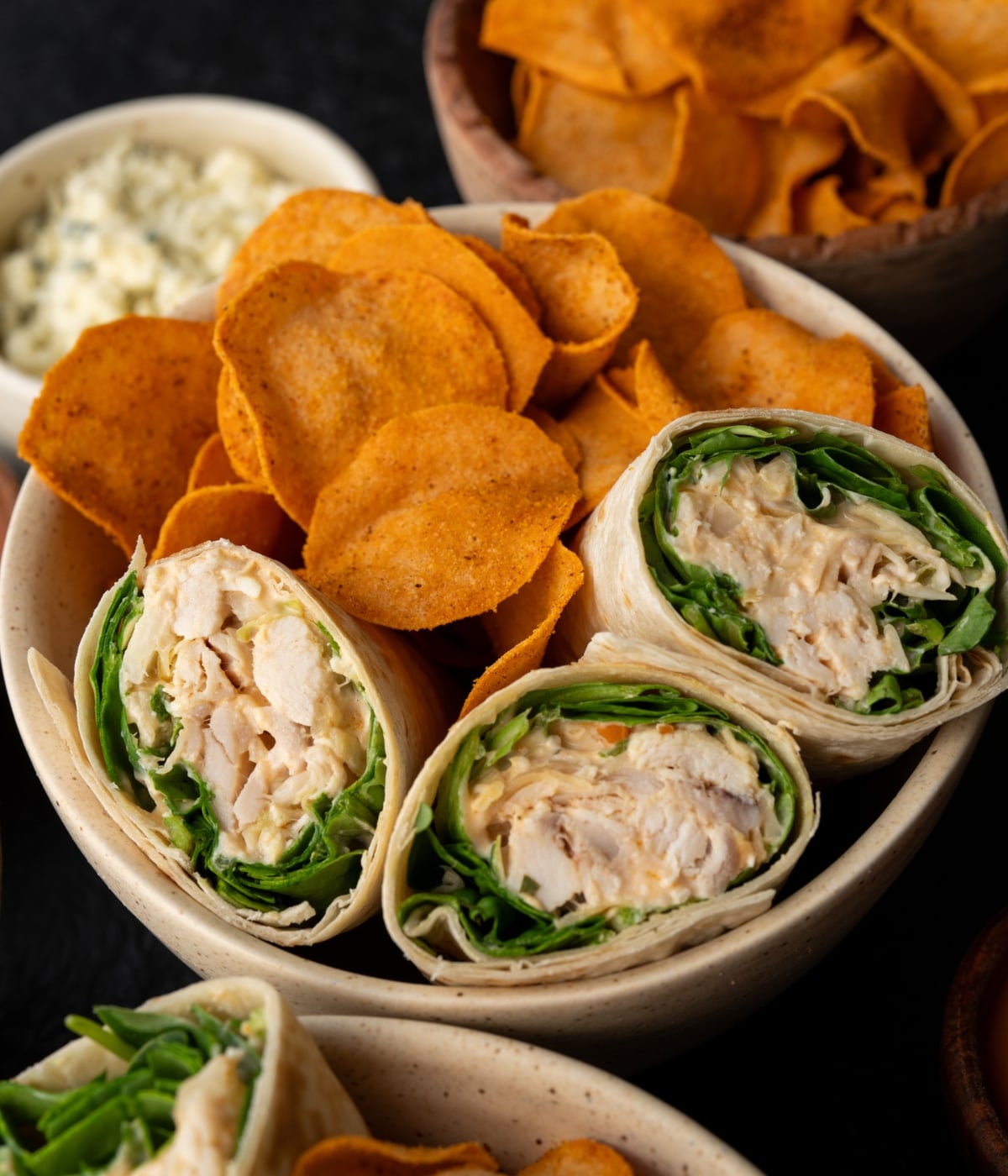 three buffalo chicken wraps with buffalo chicken chips in a bowl