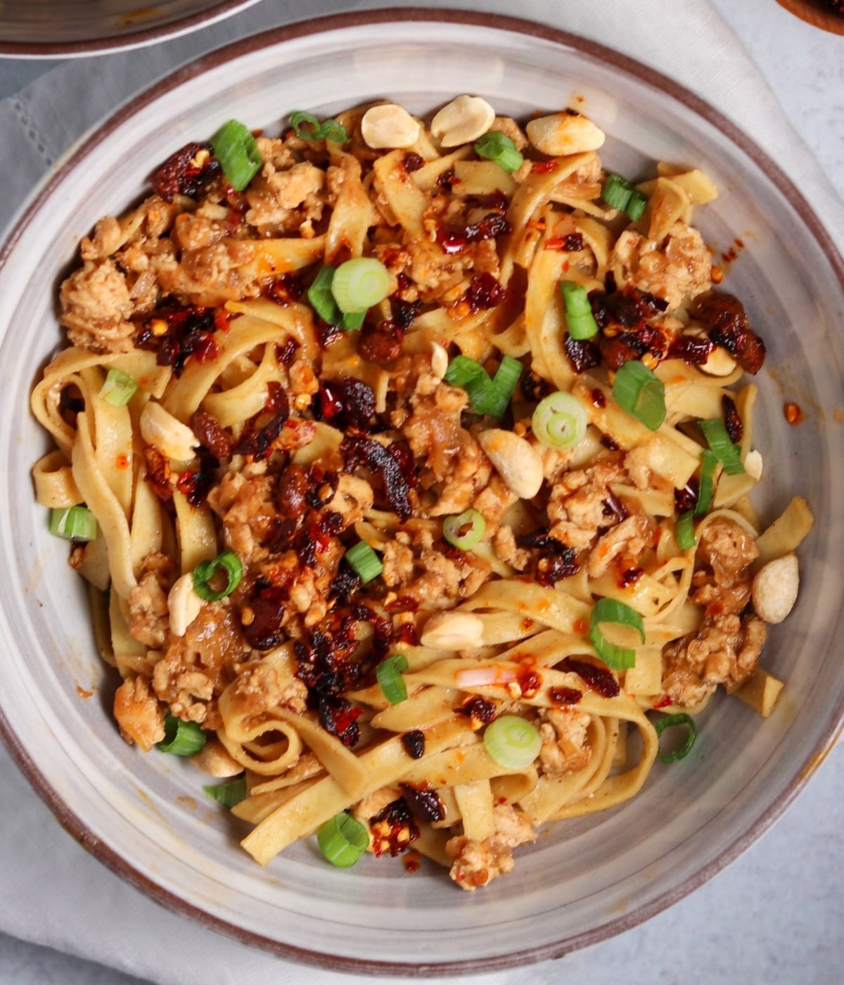 chicken dan dan noodles garnished with scallions and chili crisp