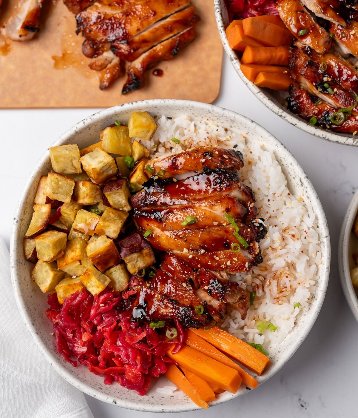 air fried chicken thigh sliced and served over steamed rice with roasted Japanese sweet potatoes, pickled cabbage and carrots