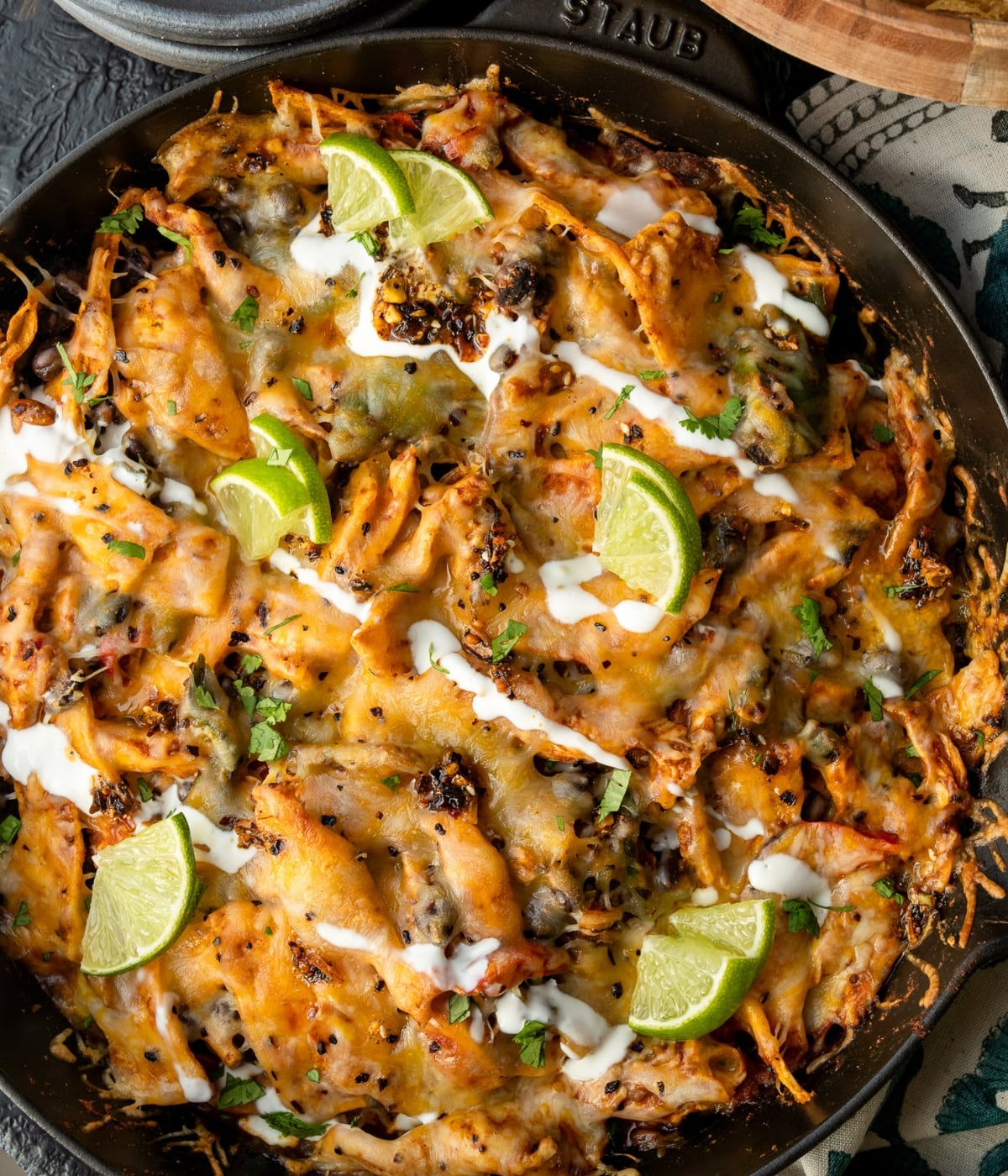 chicken fajita casserole in a cast iron pan garnished with a Greek yogurt drizzle and lime wedges