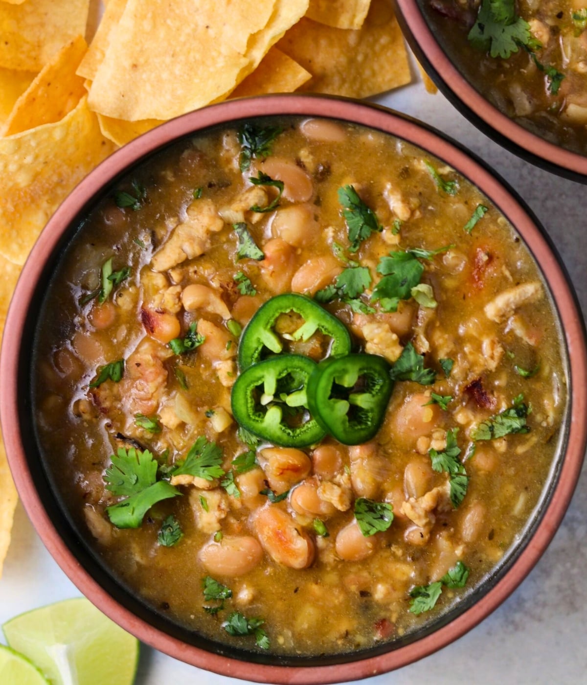 white bean ground chicken soup garnished with cilantro and jalapeño slices
