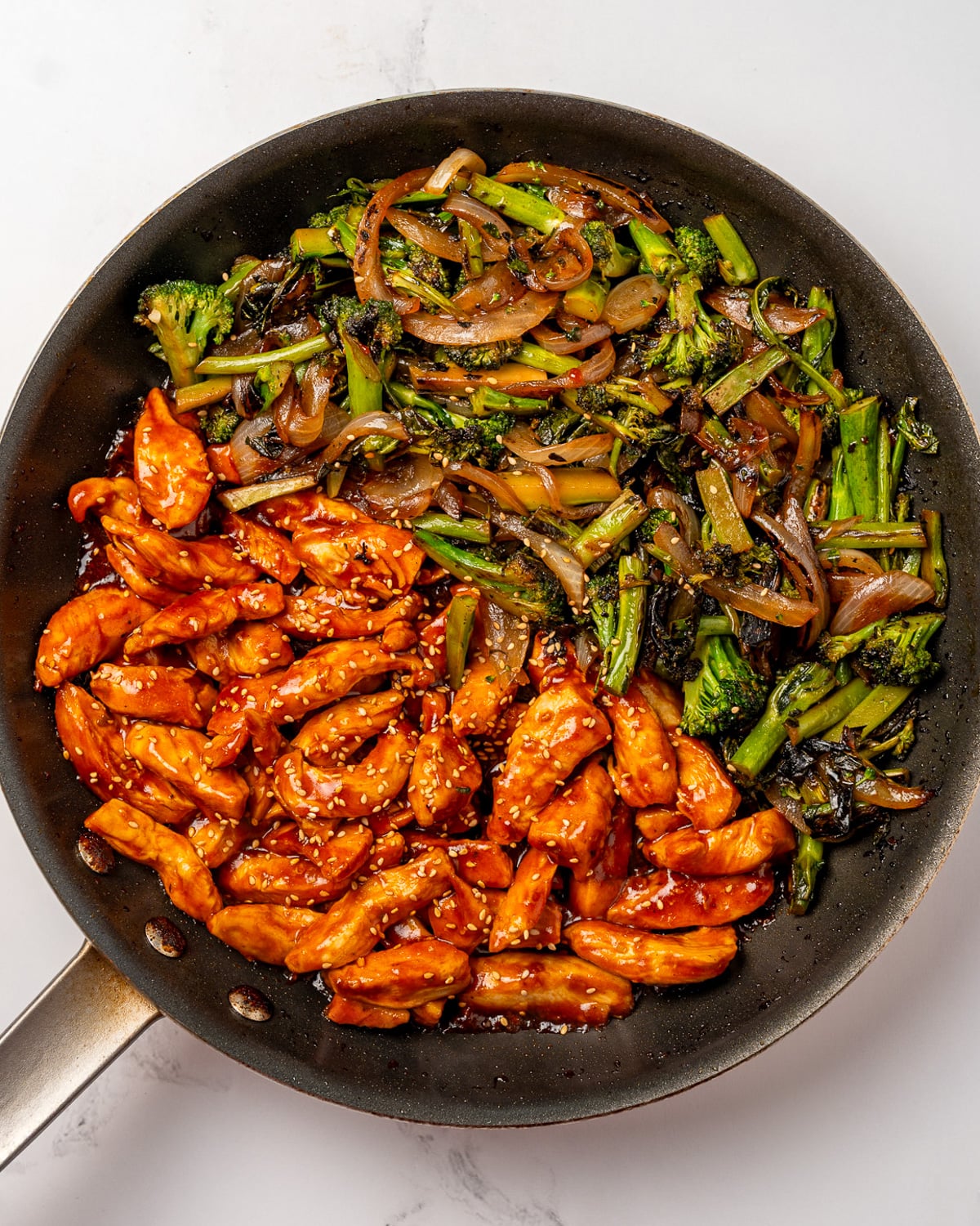 gochujang chicken breast and stir fried baby broccoli and onions in a nonstick pan