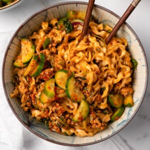 instant noodle bowls with gochujang ground chicken and veggies, pickled cucumbers, and chopsticks