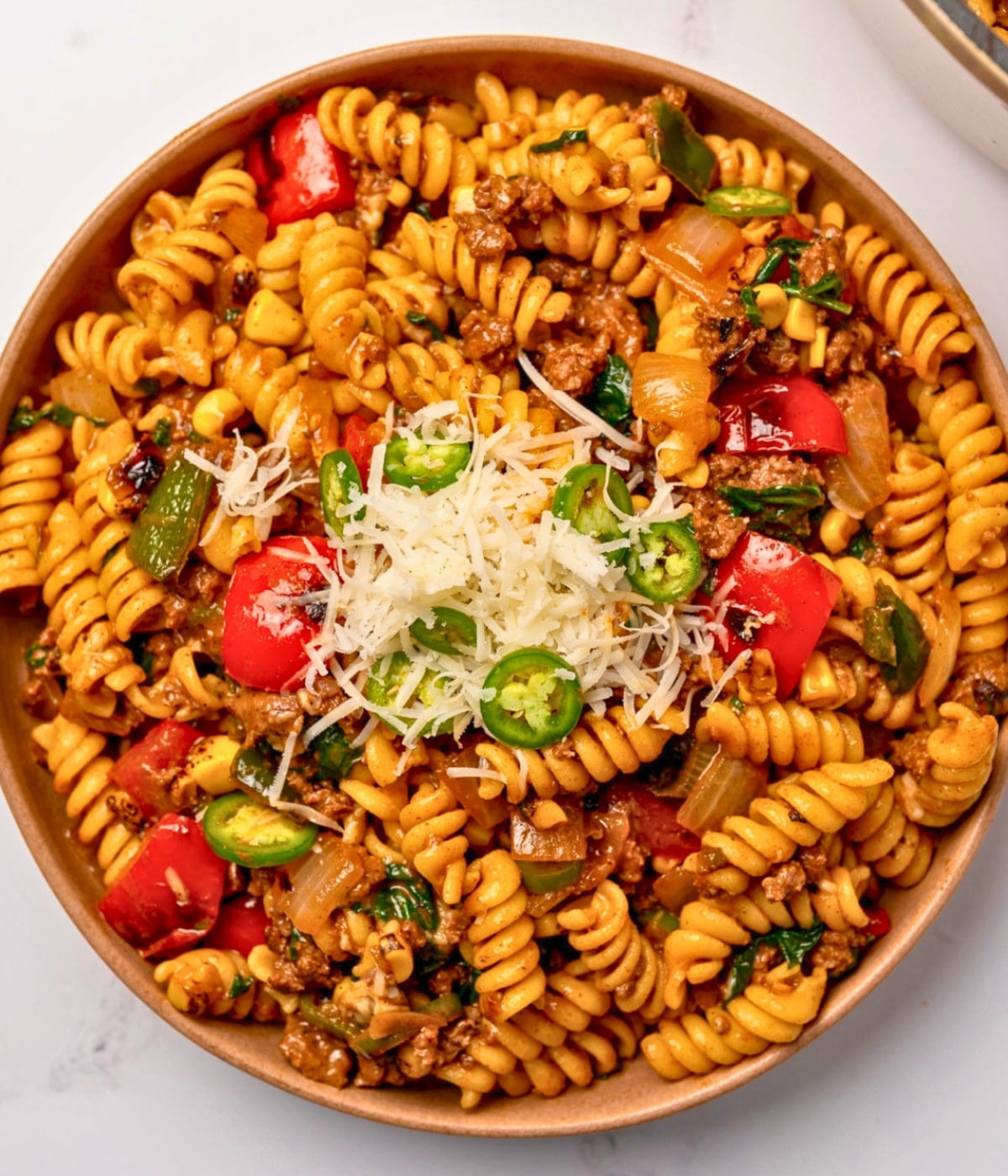 taco beef pasta in a bowl with cheese and sliced peppers