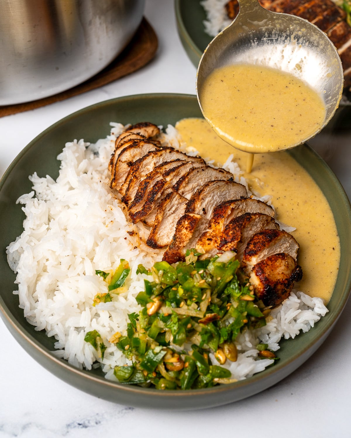 pouring creamy corn broth over rice, chicken, and jalapeño salsa