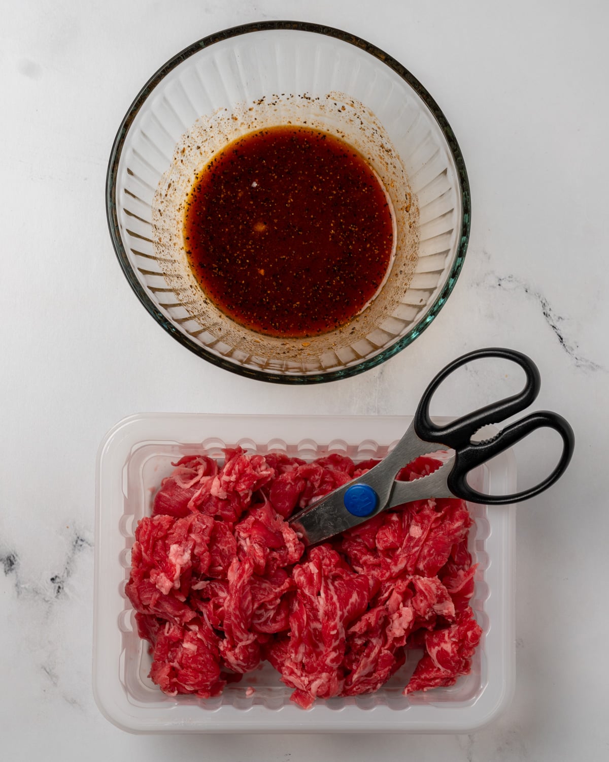 shaved steak next to a bowl of gochujang marinade