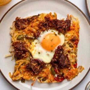 a slice of sheet pan steak and eggs on a plate garnished with chives and black pepper