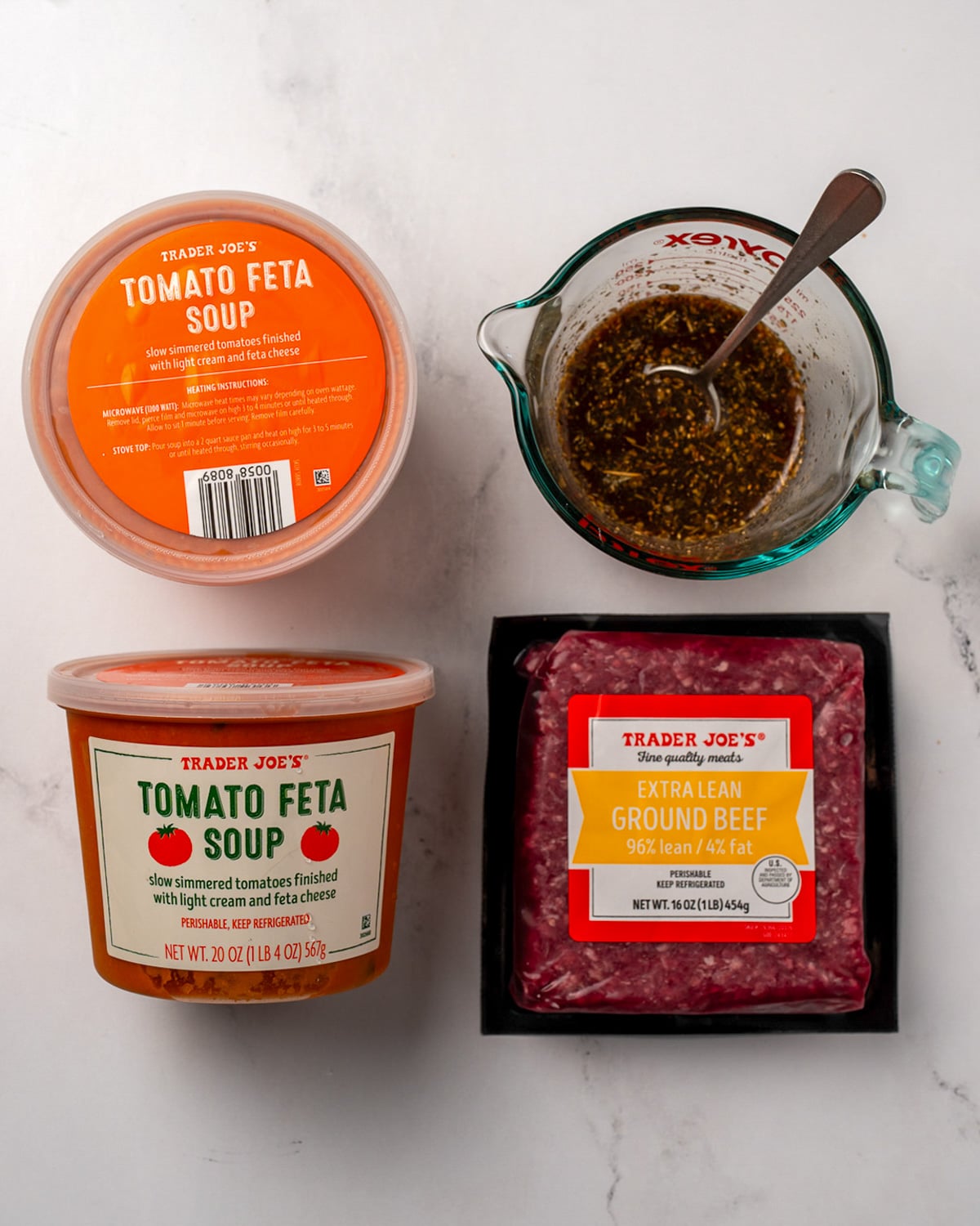 two containers of trader joe's tomato feta soup next to a pound of extra lean ground beef and a measuring cup full of balsamic sauce
