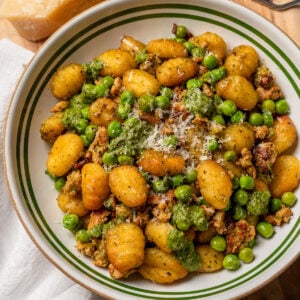 a bowl of chicken sausage gnocchi garnished with parmesan cheese and basil