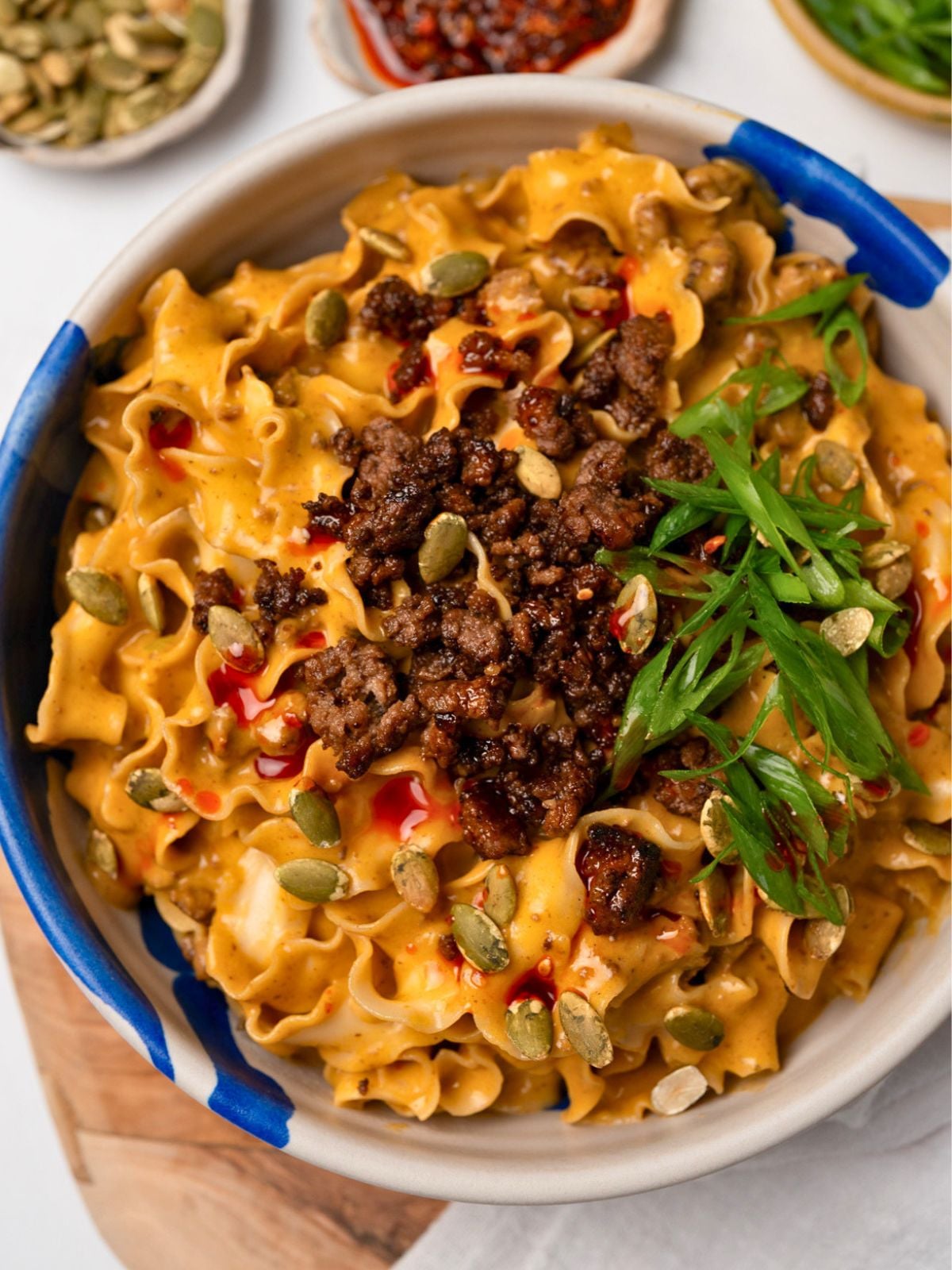 pumpkin noodles in a bowl topped with crispy beef and sliced green onion