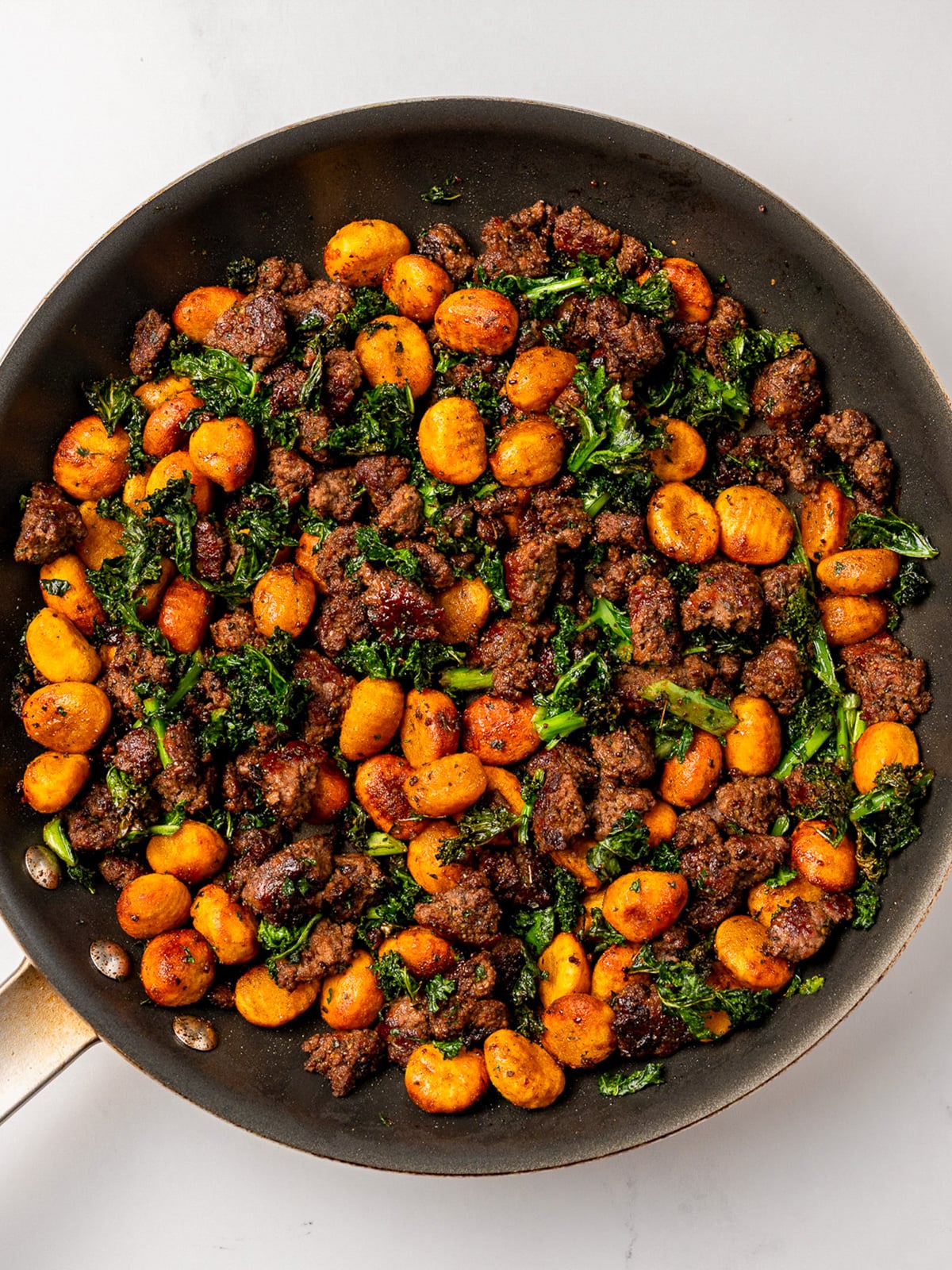 crispy roasted pumpkin gnocchi and kale in a skillet with maple balsamic ground beef