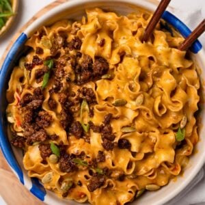 eating beefy pumpkin noodles from a bowl with wooden chopsticks