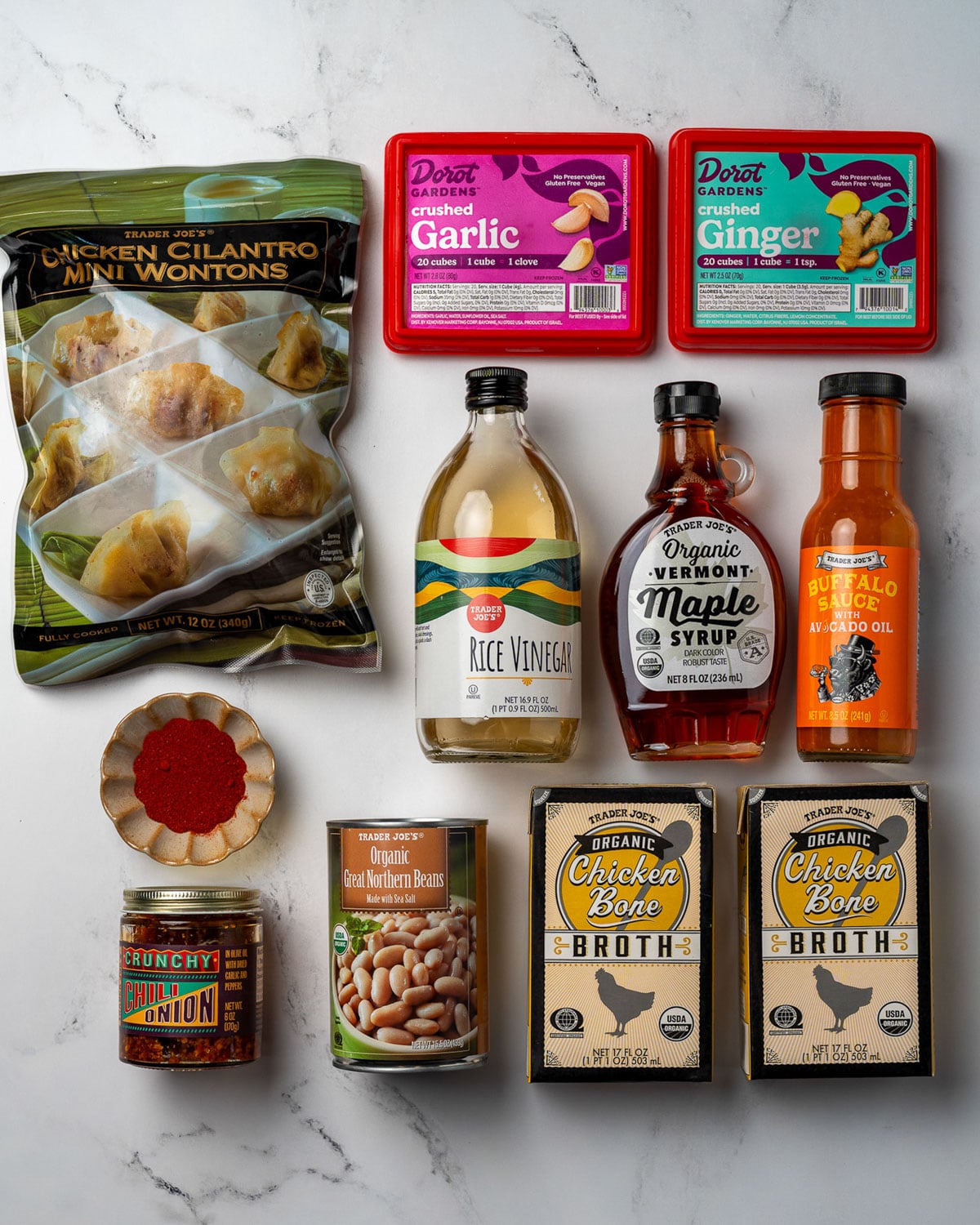 Trader Joe's frozen cilantro chicken wontons, frozen crushed garlic and ginger, rice vinegar, maple syrup, buffalo sauce, crispy chili onion, paprika, great northern beans, and chicken bone broth