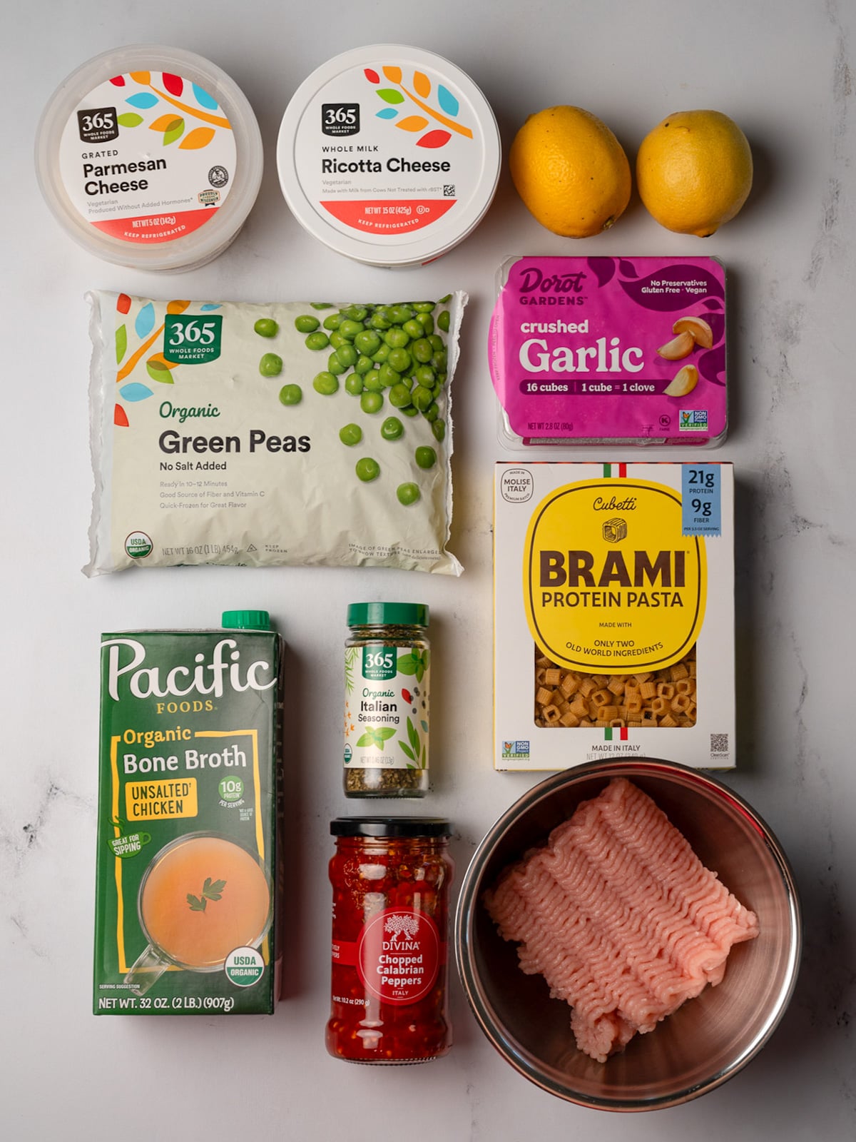 grated parmesan, ricotta cheese, two lemons, frozen green peas, frozen crushed garlic, Brami cubetti, chicken bone broth, Italian seasoning, chopped Calabrian chili peppers, and ground chicken from Whole Foods