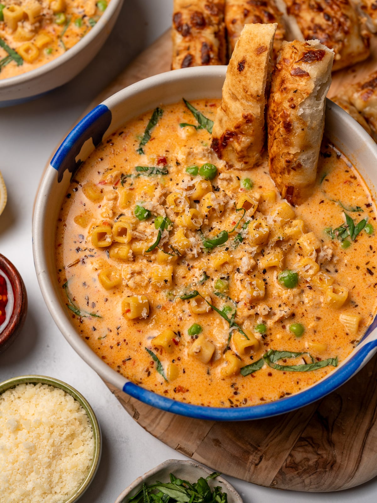 two bowls of Italian ground chicken soup with focaccia, basil, and freshly grated parmesan