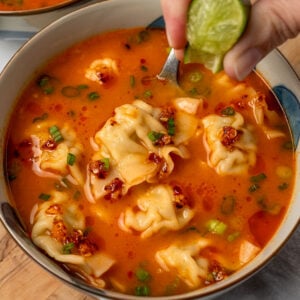 squeezing a lime over a bowl of chicken wonton soup