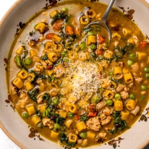 spoon in a bowl of chicken minestrone with pesto and parmesan