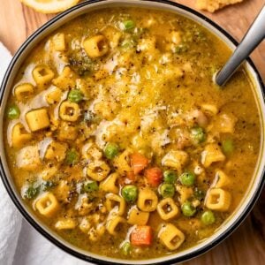 bowl of chicken pesto minestrone with parmesan crisps and a sliced lemon