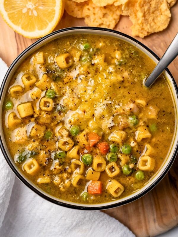 bowl of chicken pesto minestrone with parmesan crisps and a sliced lemon
