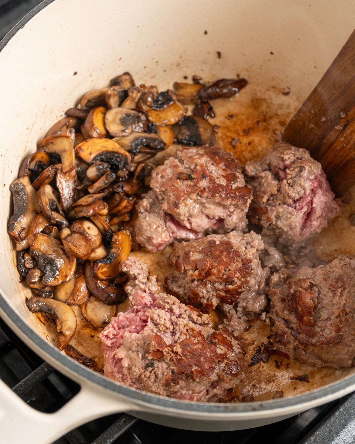 browned ground beef in a Dutch oven with browned mushrooms