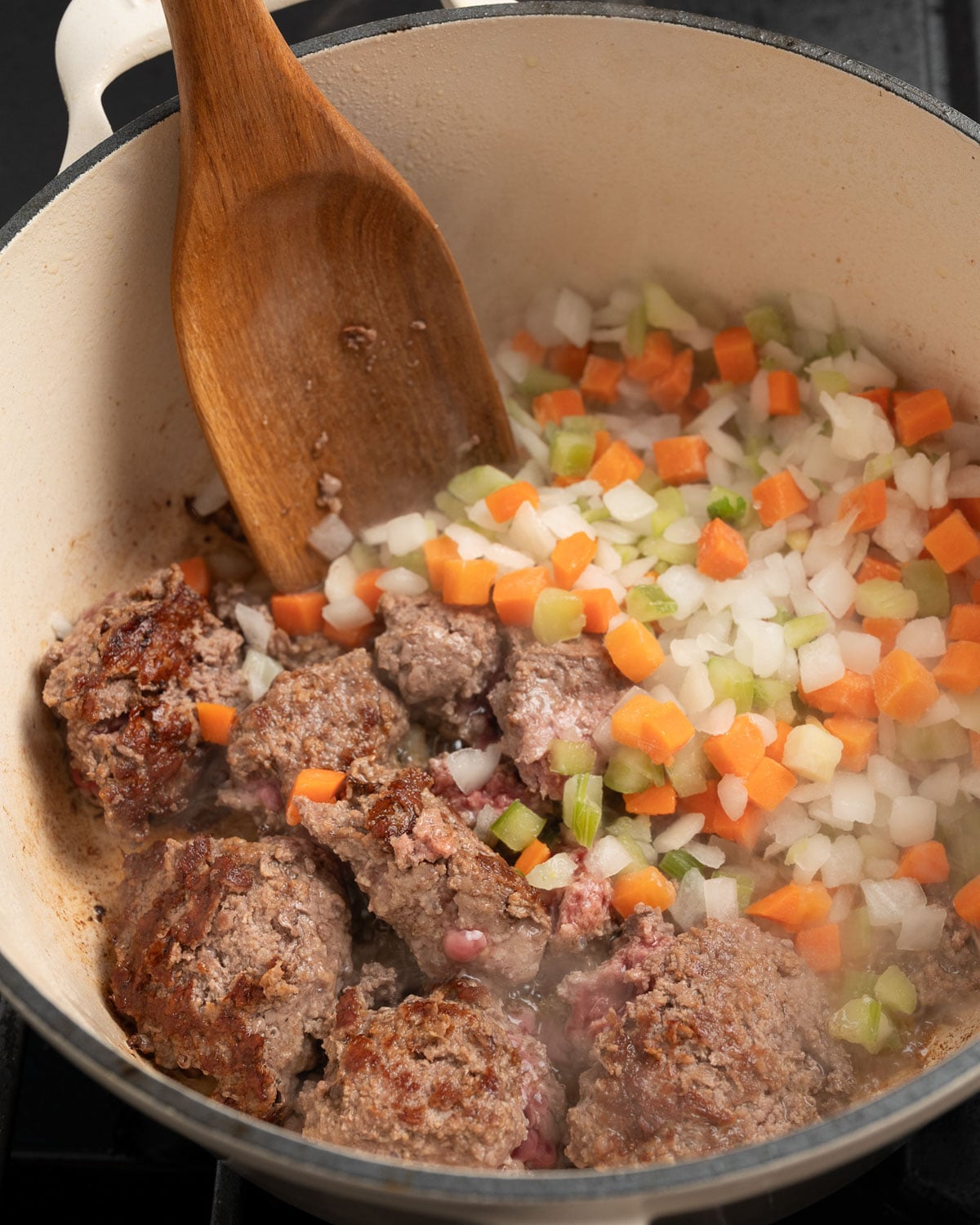 browned ground beef in a Dutch oven with frozen mirepoix