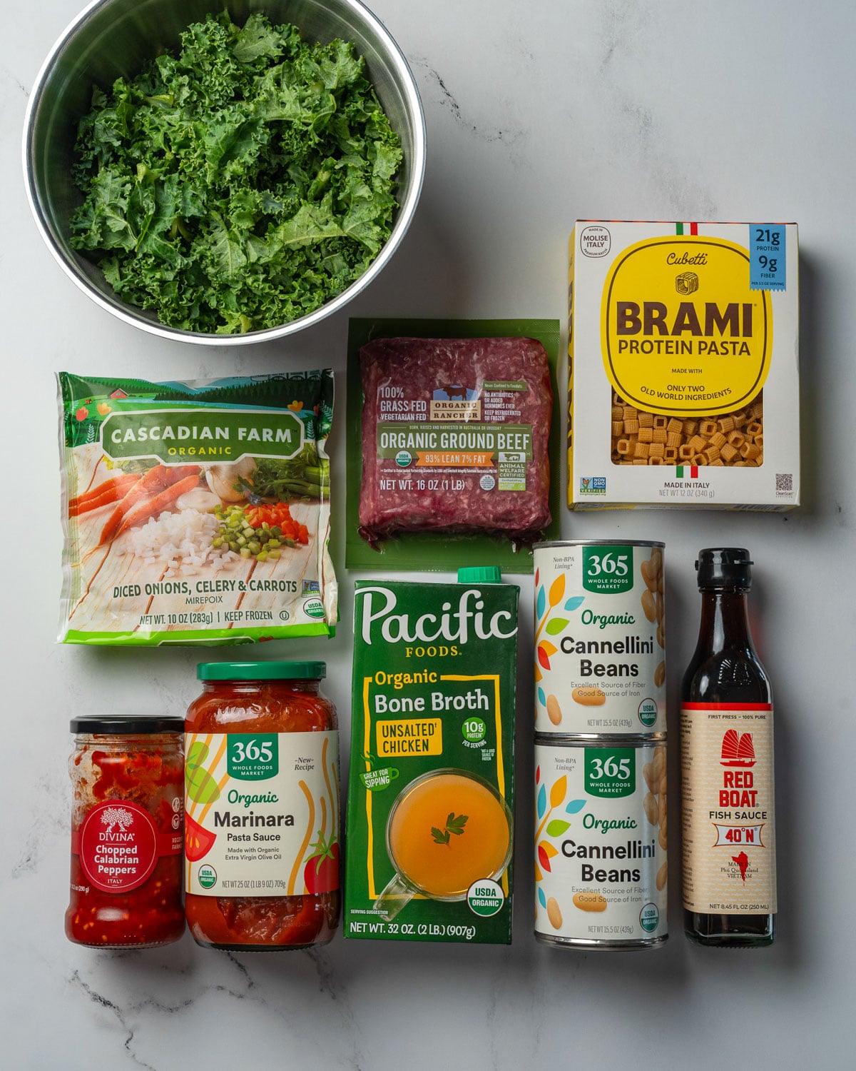 chopped kale, lean ground beef, frozen mirepoix, Brami protein pasta, chopped Calabrian chili peppers, marinara, chicken bone broth, two cans of beans, and fish sauce