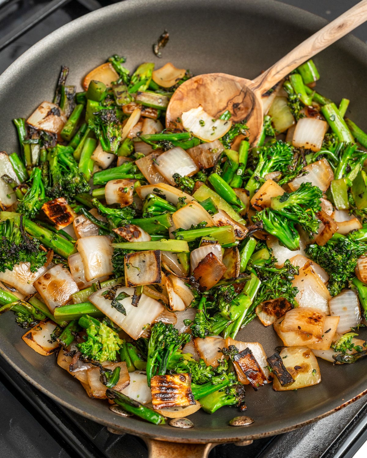 stir fried baby broccoli and onion in a pan